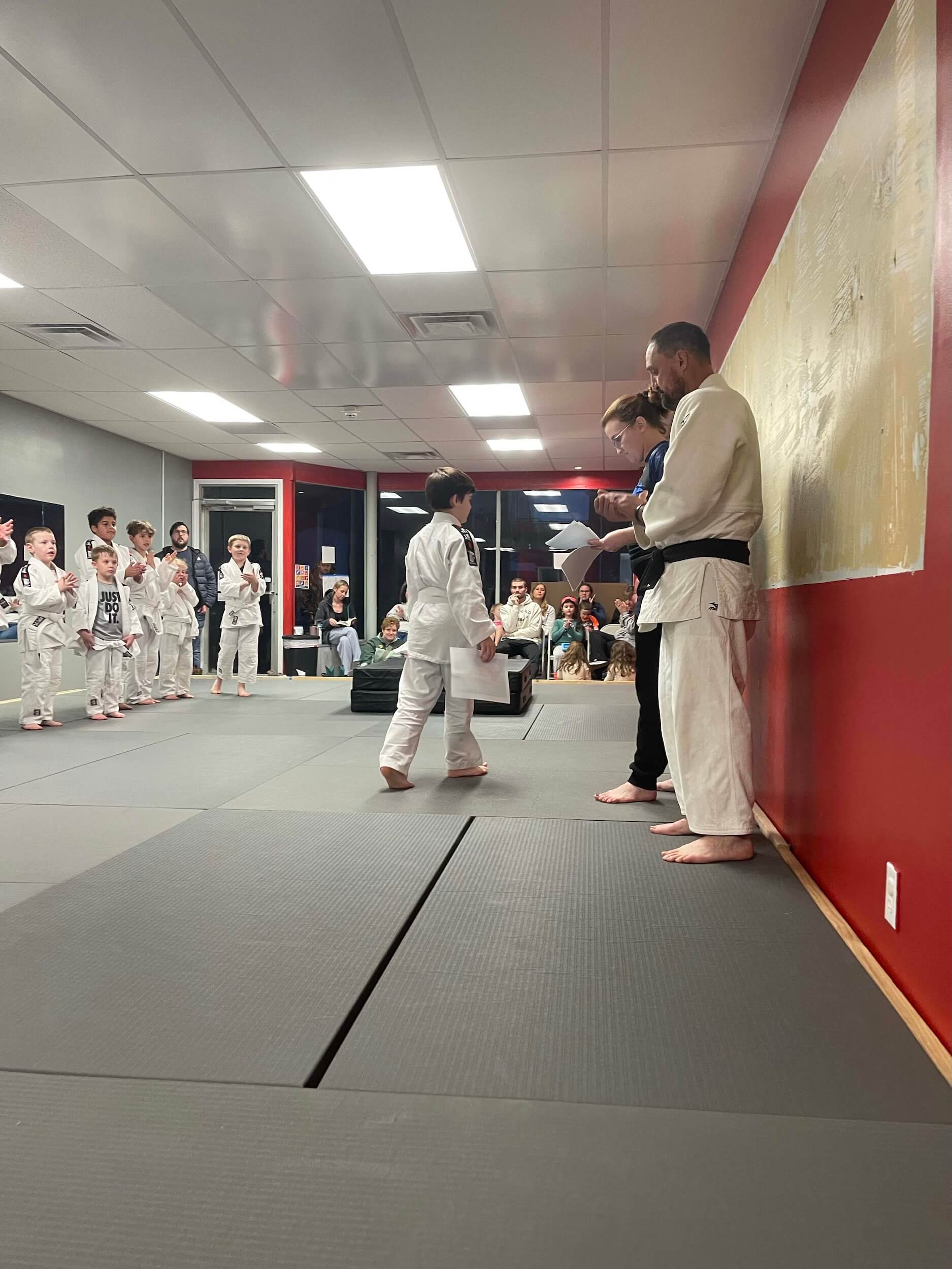 Carmel Judo students getting certificates from instructors after passing martial arts exams.